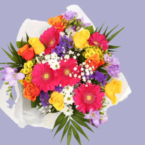 “Bright bouquet with yellow roses, pink gerberas, purple freesias, and white daisies wrapped in white paper – under £35 UK flower delivery.”