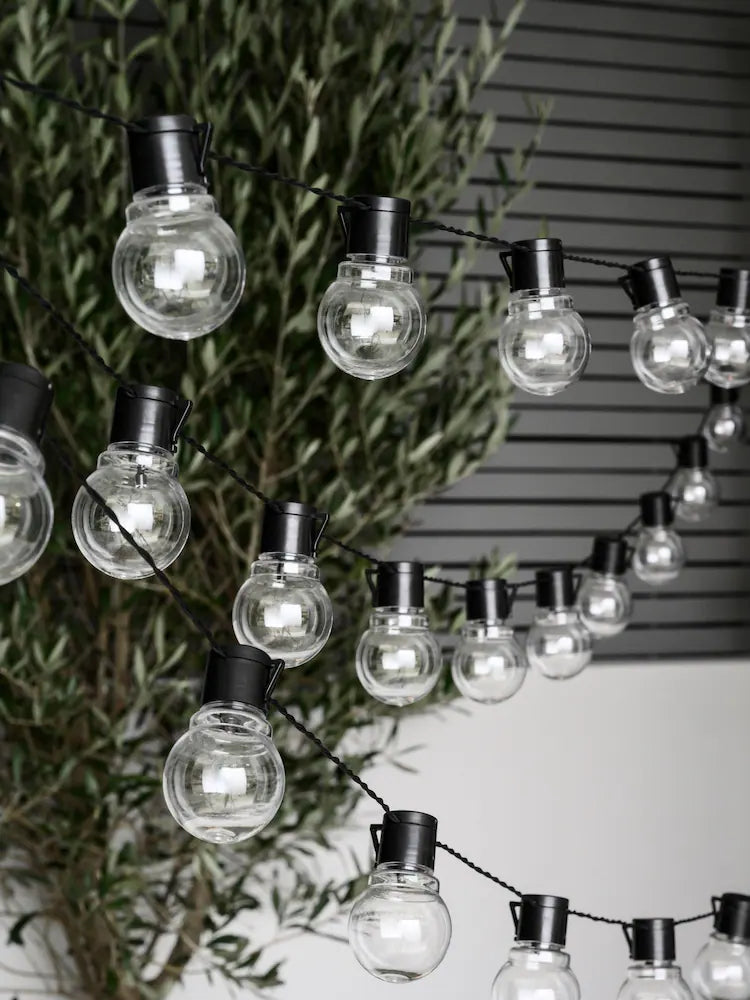 Warm white globe string lights with glowing round bulbs on black wire for festive indoor and outdoor decoration