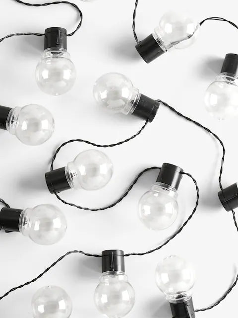 Warm white globe string lights with glowing round bulbs on black wire for festive indoor and outdoor decoration