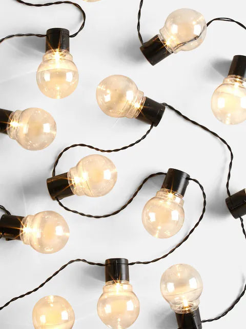Warm white globe string lights with glowing round bulbs on black wire for festive indoor and outdoor decoration