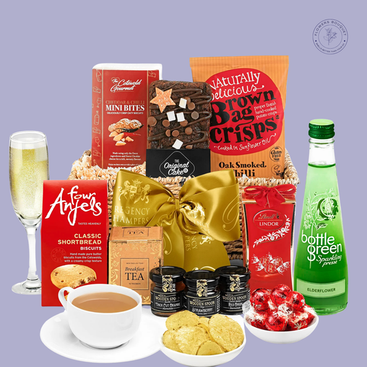 A luxurious tea-time gift hamper featuring breakfast tea bags, shortbread biscuits, jams, chocolates, crisps, brownies, and sparkling elderflower, elegantly wrapped with a golden bow.