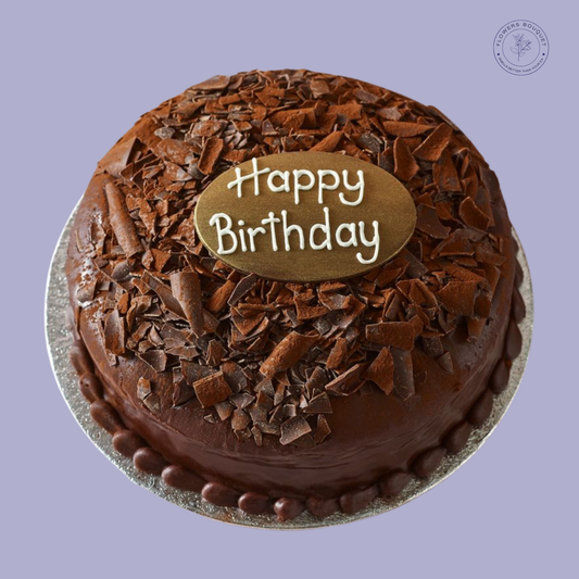 Decadent chocolate cake with chocolate ganache, shavings, and a 'Happy Birthday' plaque, perfect for celebrations.