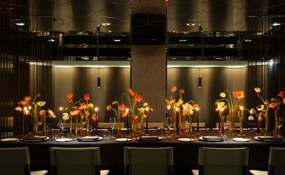 Elegant floral centerpiece with colorful poppies in gold candle holders on a formal dining table.