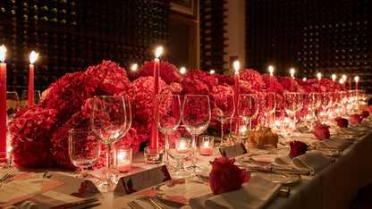 Elegant floral table centerpiece with red hydrangeas, red roses, and candles for luxury event decor.