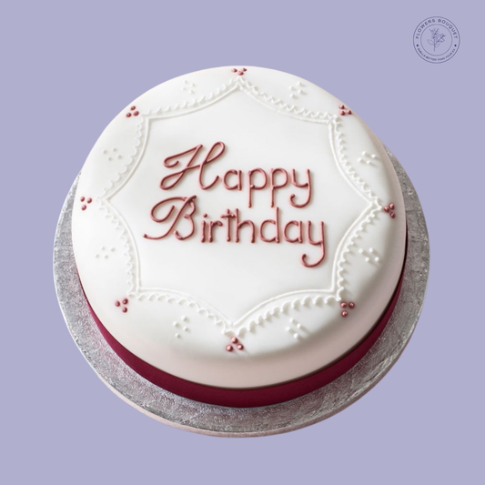 Elegant Happy Birthday cake with white fondant icing, delicate decorations, and 'Happy Birthday' written in red icing, perfect for celebrations.
