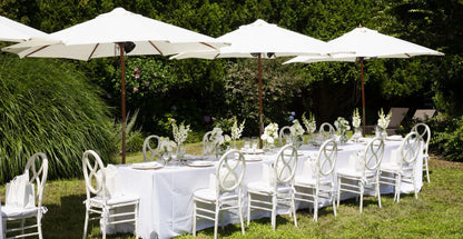 Outdoor dining setup with white flowers and glassware, perfect for garden parties and events.