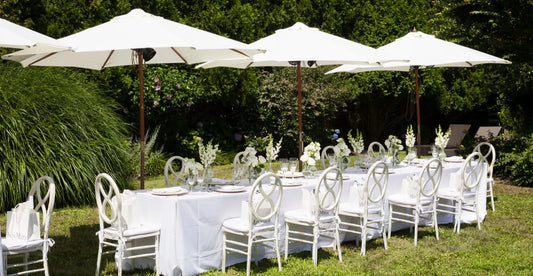 Outdoor dining setup with white flowers and glassware, perfect for garden parties and events.