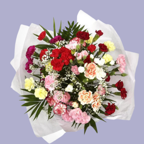 “Mixed carnation bouquet in pink, red, yellow, and peach tones with baby’s breath and greenery, wrapped in white paper – under £35 UK flowers.”