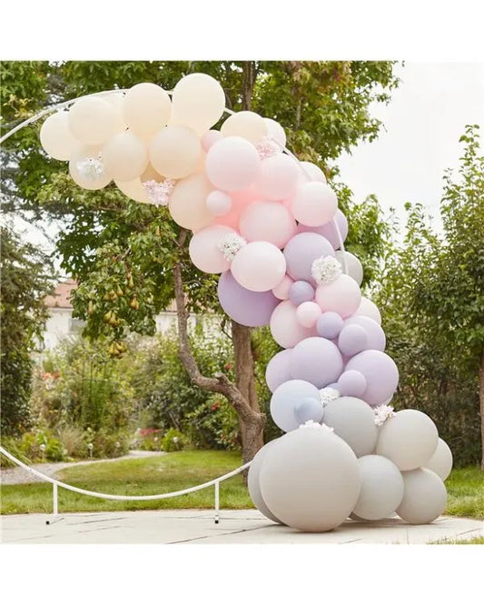 Pastel balloon arch for garden party decoration with pink, lavender, and cream balloons outdoors.