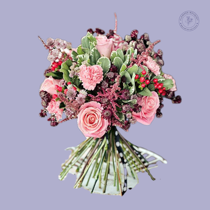 Romantic bouquet of pink roses, carnations, and berries in a glass vase with a polka dot ribbon.