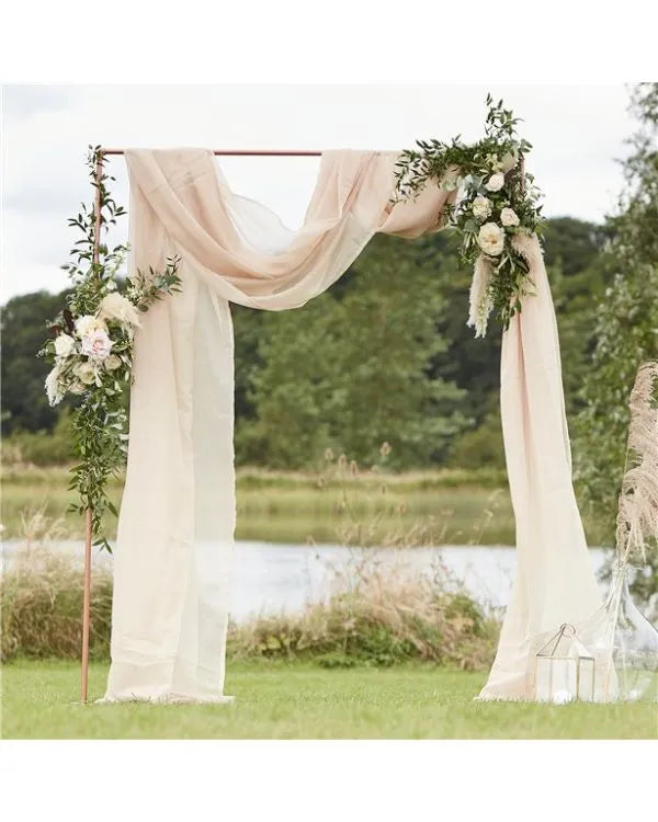 Rustic wedding arch with ivory drapes, greenery, and white roses – perfect for outdoor UK wedding ceremony decoration.