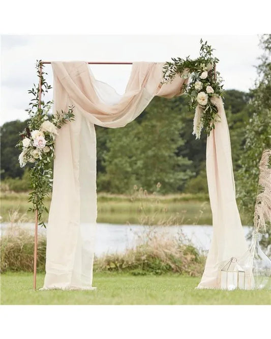 Rustic wedding arch with ivory drapes, greenery, and white roses – perfect for outdoor UK wedding ceremony decoration.