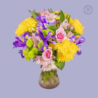 "Vibrant bouquet with pink roses, yellow chrysanthemums, and purple irises in a glass vase, perfect for any occasion."