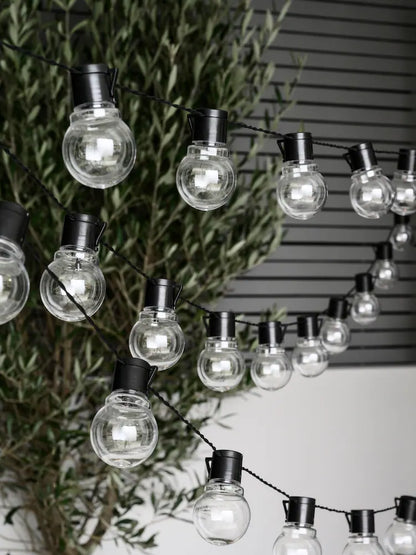 Warm white globe string lights with glowing round bulbs on black wire for festive indoor and outdoor decoration