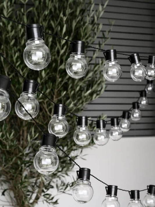 Warm white globe string lights with glowing round bulbs on black wire for festive indoor and outdoor decoration