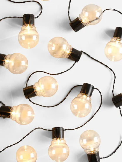 Warm white globe string lights with glowing round bulbs on black wire for festive indoor and outdoor decoration